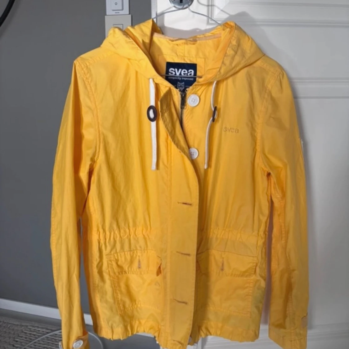 Gul vindjacka med huva från Svea