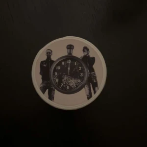 12 TILL 12 X-STRONG Snusdosa - Tom snusdosa med unikt tryck av klocka och två personer på locket. Märkt 'X-STRONG' och 'ADEN + ASME'.  Qr cod funkar att scanna så att man kommer in på 12 till 12 spellistan.