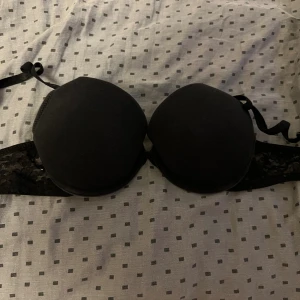 Svart Bh från H&M - Svart BH från H&M med vadderade kupor och spetsdetaljer på sidorna. Axelbandslös design som ger en clean look under kläder. Perfekt för dig som vill ha en enkel men snygg topp till din outfit.