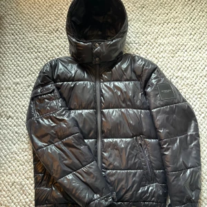 Svart pufferjacka från Michael Kors - Snygg vinterjacka i glansigt material perfekt till höst och vinter! Jackan är från Michael kors och är använd en vinter! Nypris 4399kr! Undvik inte att ställa frågor💪👏
