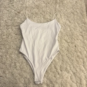 Vit body från Zara, storlek M - Supersnygg vit baddräkt från Zara med tunna axelband och enkel, stilren design. Materialet är mjukt och följsamt, perfekt för strandhäng eller poolparty. Passformen är normal och färgen är helvit, vilket gör den lätt att matcha med andra sommaraccessoarer.