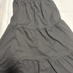 Svart långkjol från LGT i XS - Svart långkjol från LGT i storlek XS. Kjolen har flera volanger och resår i midjan för en bekväm passform. Tillverkad i ett lätt och luftigt tyg som ger ett snyggt fall. Perfekt för dig som gillar en enkel men stilren look. Använt 1 gången, den är superfin men inte riktigt min stil, priset kan diskuteras.