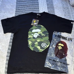 BAPE T-shirt - Säljer denna snygga Bape T-shirten för den passar inte mig. Skicket är lika gott som nytt, har blivit använt men inga skador/defekter alls. Tags och påse medföljer. Pris går att diskuteras vid snabb affär! Om du har frågor, hör av dig!🫡