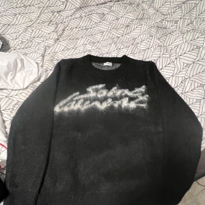 Svart Saint Laurent stickad  - Saint Laurent stickad tröja i svart med vit “Saint Laurent”.  mjukt, bekvämt tjockt material. Storlek S, men passar bättre som M – sitter lite baggy på mig.