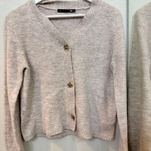 Beige kofta med knappar - Mysig beige kofta från H&M med v-ringning och tre stora knappar framtill. Långärmad och stickad i mjukt material, perfekt för lager-på-lager och chill dagar. Enkel och stilren design som funkar till det mesta.