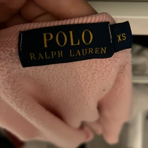 Rosa sweatshirt från Polo Ralph Lauren XS - Superfin ljusrosa sweatshirt från Polo Ralph Lauren i bomull. Klassisk modell med rund hals, ribbade muddar och blå logga broderad på bröstet. Perfekt för en chill och stilren look.