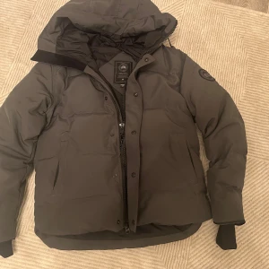 Canada Goose Macmillan Grå dunjacka S - Stilren och varm grå dunjacka från Canada Goose i storlek S – perfekt för vintern och kyliga dagar! 🖤 Skön passform som sitter bekvämt med gott om värme 🔥 Flera praktiska fickor både på insidan och utsidan ✔️ Tidlös design som passar både till vardags och mer uppklätt 🧥 Fint skick ✨  Perfekt för dig som vill ha en snygg och funktionell vinterjacka. Skickar samma dag eller dagen efter! Skicka PM vid frågor 💬 