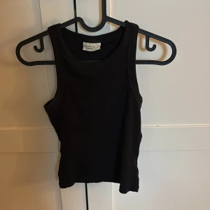 Svart ribbad linnetopp - Säljer en svart ribbad linnetopp. Toppen är ärmlös med klassisk rund halsringning och har en tight passform. 