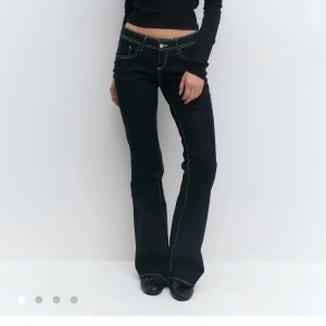 Mörkblå bootcut jeans med kontrastsömmar - Snygga mörkblå jeans med låg midja och bootcut-ben. Jeansen har tydliga vita kontrastsömmar och klassisk femficksdesign. Perfekta för dig som gillar en retrovibe och vill ha ett par jeans som sticker ut lite extra. Endast testade men för små! Kan tänka mig byta mot storlek 40