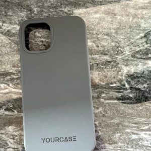 YOURCASE mobilskal - Snyggt och stilrent grått mobilskal från YOURCASE, designat för moderna smartphones med stor kameramodul. Skalet är i gott skick utan synligt slitage och ger bra skydd mot repor och stötar. Perfekt för dig som vill ha ett enkelt och funktionellt skydd.