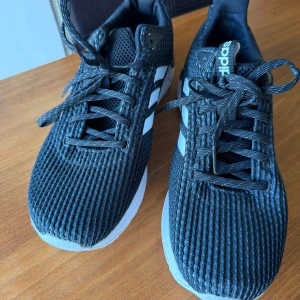 Svarta Adidas Questar Ride sneakers  - Svarta Adidas Questar Ride sneakers med klassiska vita ränder på sidorna. Ovandel i ventilerande mesh och snörning framtill. Skorna har vit och svart sula med tydligt mönster för bra grepp. Perfekta för dig som gillar sportig och stilren look. SOM NYA