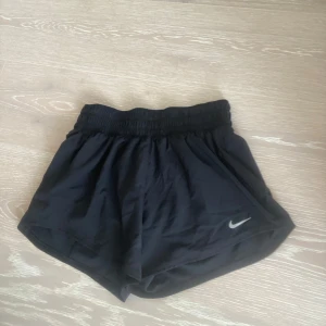 Nike Dri-Fit svarta träningsshorts XS - Helt oanvända Svarta Nike Dri-Fit shorts i loose fit med elastisk midja och klassisk silverfärgad swoosh-logga. Perfekta för träning eller löpning, tillverkade i ett lätt och snabbtorkande syntetmaterial som andas. Sportig och enkel design med bekväm passform. 