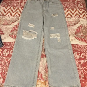 Ljusblå ripped jeans från SHEIN Teen - Ljusblå jeans från SHEIN Teen 14y med breda raka ben och flera slitna detaljer framtill. Klassisk femficksmodell med hög midja och dragkedja med knapp. Jeansen är tillverkade i bomull och har en avslappnad, trendig vibe. 