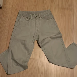 Beige raka jeansbyxor - Snygga beige jeansbyxor med klassisk femficksdesign och raka ben. Byxorna har bälteshällor, knapp och dragkedja framtill samt diskreta nitar vid fickorna. Perfekta för en clean och stilren look.