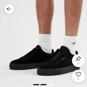 Axel Arigato 360 - Stilrena svarta sneakers från Axel Arigato i mocka med diskret guldfärgad logga på sidan. Skorna har en platt sula och minimalistisk design utan synlig snörning, vilket ger en clean look. Perfekta för dig som gillar enkel och modern stil.