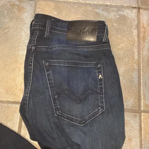 Replay Grover straight fit jeans blå st. 28/32 - Helt nya! Snygga mörkblå Replay Grover jeans i straight fit i storlek 28/32 med klassisk femficksdesign och tydliga Replay-detaljer. Jeansen har en rak passform, knappgylf och coola slitningar för en avslappnad look. Perfekta för dig som gillar stilrena och tidlösa jeans. 