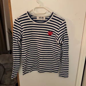 Comme des Garçons tröja - Säljer en randig långärmad tröja från Comme des Garçons Play i vitt och marinblått. Tröjan är i gott skick och storlek S.