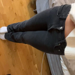 Svarta bootcut jeans - Säljer ett par svarta jeans med bootcut-modell och klassisk femficksdesign. Jeansen har lågmidja och är tillverkade i stretchigt denimtyg som sitter snyggt. 