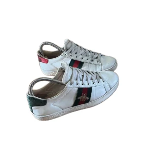 sneakers med bi-detalj - sneakers i vitt skinn med klassiska gröna och röda ränder på sidan och broderad guldfärgad bi. Hälpartiet har grön och röd metallicdetalj. Platt sula och snörning framtill. Perfekta för dig som vill sticka ut med lyxig streetstyle.