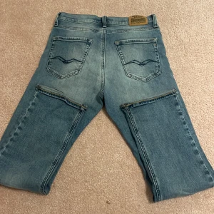 Replay ljusblå raka jeans - Säljer ett par ljusblå jeans från Replay med klassisk femficksdesign och raka ben. Jeansen har snygga slitningar och detaljerade bakfickor med broderi. Materialet är mjukt denim och passformen är normal. Jag har aldrig användt dem men texten på märkeslappen har rivits av med tiden. Perfekta för dig som gillar en avslappnad stil. 