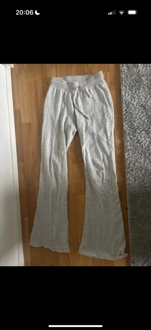 Grå bootcut mjukisbyxor från Zara - Säljer ett par ljusgrå mjukisbyxor från Zara i storlek S. Byxorna har bootcut-ben, resår i midjan och snörning framtill. Mjukt och skönt material i bomullsmix, perfekta för chill dagar hemma. Enkla att matcha med hoodies eller t-shirts.
