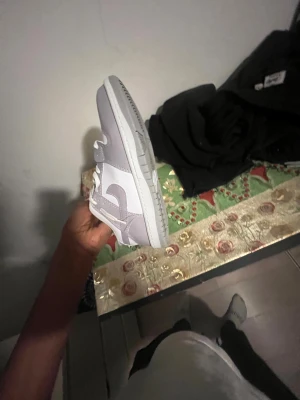 Nike Dunk Low vit och ljusgrå - Nike Dunk Low sneakers i en clean kombo av vit och ljusgrå. Skon har klassisk rund tå, platt sula och snörning framtill. Ovandelen är i syntet och skinn med perforering på tån för extra ventilation. Swoosh-loggan på sidan och Nike-text bak ger en snygg touch.