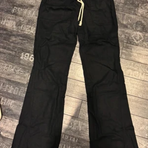 Svarta linnebyxor från Roxy med snörning - Svarta linnebyxor från Roxy med avslappnad passform och snörning i midjan. Byxorna har raka ben, praktiska fickor fram och bak samt en broderad logga på bakfickan. Perfekta för chill dagar och enkel stil. Helt nya aldrig använda. Lappen och förpackning är kvar. 