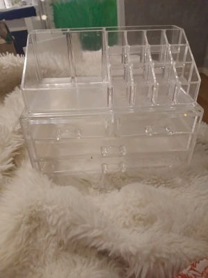 Transparent sminkförvaring med lådor - Säljer en genomskinlig sminkförvaring i akryl med flera fack och tre utdragbara lådor. Perfekt för att organisera sminkborstar, läppstift, ögonskuggor och andra produkter. Modern och stilren design som passar på sminkbordet.
