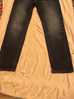 Mörkblå raka jeans från Lee - Snygga mörkblå jeans från Levi's med klassisk rak passform och subtila slitningar framtill. Jeansen har fem fickor och är tillverkade i robust denim som ger en cool och tidlös look. Perfekta för dig som gillar enkel och stilren design.