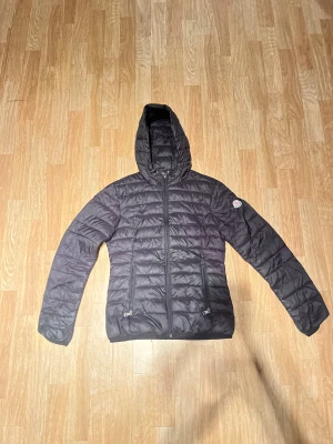 Svart Moncler dunjacka med huva - Äkta svart dunjacka från Moncler med huva och två dragkedjeförsedda fickor. Säljer billigt. Först till kvarn!