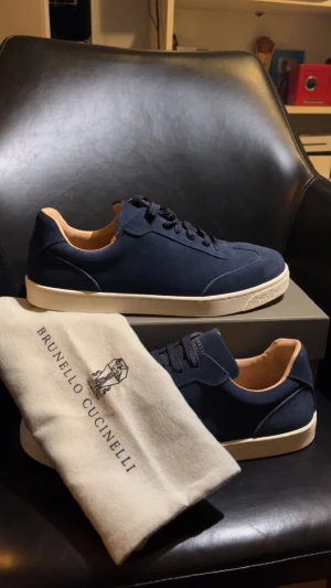 Brunello Cucinelli skor - Snygga mörkblå sneakers från Brunello Cucinelli i mocka med vita, platta gummisulor och klassisk snörning. Insidan är ljusbeige och skorna har en stilren, minimalistisk design. Perfekta för dig som gillar exklusiva och tidlösa sneakers.1:1