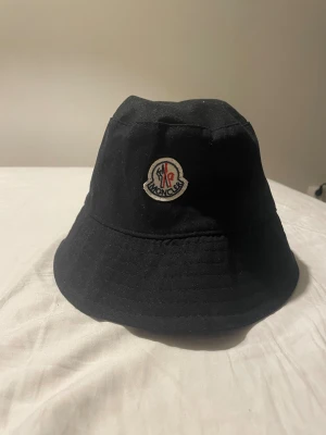 Svart Möncler hatt - Varan är i väldigt bra skick. Perfekt för sommaren som skyddar dig i solen med stil. 