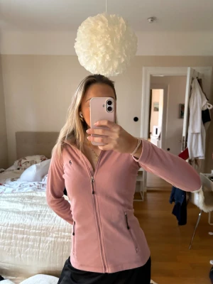 Rosa fleecekofta Peak Performance S - Mjuk och skön rosa fleecekofta från Peak Performance i storlek S. Koftan har hel dragkedja framtill, två sidofickor med dragkedja och diskret logga på bröstet. Perfekt för kyliga dagar och enkel att slänga på sig över en t-shirt. Även prefekt i skidbacken. Använd ett fåtal gånger. 