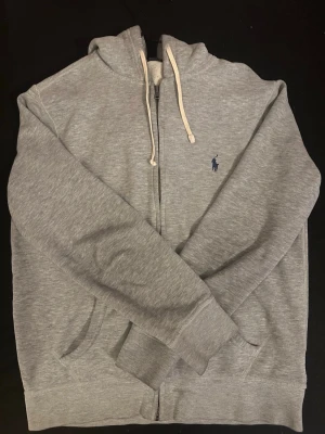Grå Ralph Lauren - Zip hoodie  - Säljer en klassisk och stilren Ralph Luaren zip-hoodie i ljusgrå melerad färg. Den är bra god skick med lite defekter. Har ni frågor är det bara att skriva! 