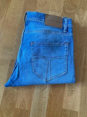 Blå jeans från Tiger of Sweden - Snygga blå jeans från Tiger of Sweden med klassisk femficksdesign och ljus tvätt. Jeansen har raka ben och normal passform.Materialet är mjukt jeans i bomull och de har en stilren look som funkar till många outfits.
