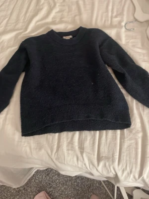 Mörkblå stickad tröja - Säljer en enkel och snygg mörkblå stickad tröja med rund hals och långa ärmar. Perfekt för kyliga dagar och passar till både jeans och kjol. Materialet är mjukt och ger en skön känsla mot huden.