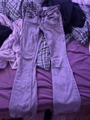 Grå bootcut jeans - Säljer ett par gråa jeans med bootcut-snitt. Byxorna har klassisk femficksdesign och är tillverkade i jeansmaterial. Passformen är normal och färgen är en ljusgrå ton som passar till många olika stilar.