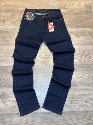 Jacob Cohën  - Snygga mörkblå jeans från Jacob Cohën i klassisk rak modell. Byxorna har fem fickor, orange kontrastsömmar och knappgylf. Materialet är högkvalitativ jeans med exklusiv känsla. Perfekt för dig som vill ha stilrena och tidlösa jeans med premiumdetaljer.