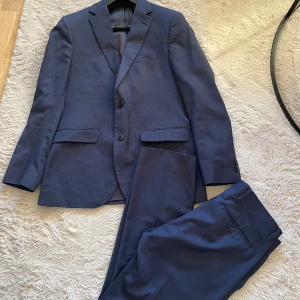 Blå kostym från Riley Regular Fit - Snygg blå kostym från Riley med regular fit storlek 48 i både kavajen och byxorna, fråga gärna om mått om det skulle behövas