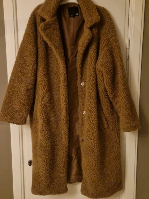 Lång kappa - Säljer en brun/beige teddykappa i stl M från Lager157. Mkt fint skick. Väldigt varm och gosig. Stängs med tryckknappar.  Hund finns i hemmet. 