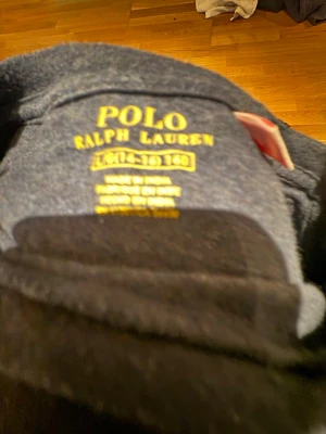 Mörkblå långärmad t-shirt Polo Ralph Lauren - Snygg mörkblå långärmad t-shirt från Polo Ralph Lauren med klassisk röd logobrodyr på bröstet. Rund hals och mjukt bomullsmaterial som känns skönt mot huden. Perfekt för dig som gillar stilrena och tidlösa plagg med en sportig touch.