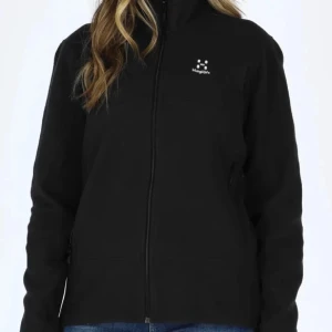 Svart fleecejacka från Haglöfs - Svart fleecejacka från Haglöfs med dragkedja framtill och hög krage. Jackan har en enkel och stilren design med liten logotyp på bröstet. Perfekt för svalare dagar.