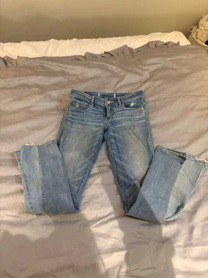 Blå jeans från Abercrombie & Fitch - Säljer ett par klassiska blå jeans från Abercrombie & Fitch med slitna detaljer och råa kanter vid bensluten. Jeansen har fem fickor, gul kontrastsöm på bakfickorna och en snygg tvättad look. Är omsydda till bootcut men omsydda snyggt så inget man tänker på bara en snygg detalj! MIDJEMÅTT:37cm som en xs/s. LÄNGD: passar mig bra nästan åt längre hållet o som är ca 161 men skulle säga att dom passar 160-170 ungefär. Kan gå ner i pris vid snabb affär!