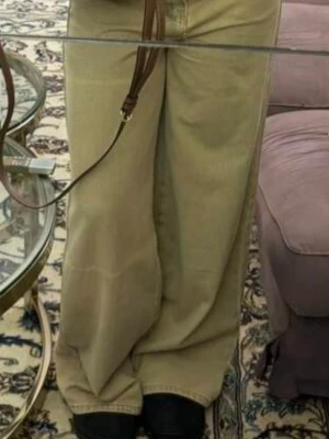 Beiga wide jeans med raka ben - Säljer ett par beiga jeans med bred passform och raka ben. Byxorna har klassiska fem fickor, hällor för bälte och stängs med dragkedja och knapp. Materialet är jeans och färgen är en kaki: beige ton som passar till det mesta. Upplaggda och benen är 74cm från skrevet och ner