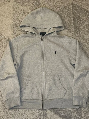 Grå Ralph lauren zip - Säljer denna gråa Ralph lauren zippen. Nästan helt ny, inga defekter! Passar ca 165-170cm. Skriv vid frågor.