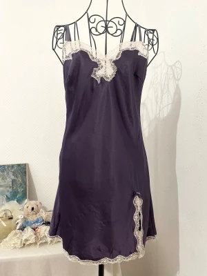 Lila nattlinne från Victoria's Secret - Supersöt lila nattlinne från Victoria's Secret med tunna axelband och vit spetsdetalj vid halsringning och nederkant. Klänningen har några rosa fläckar i nedre kant (se 2 sista bilder). Storlek: S, passar 34-36. Dockans storlek: S