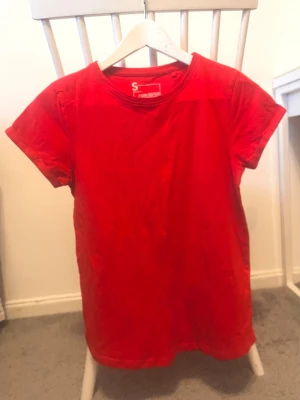Röd t-shirt - Snygg röd t-shirt i storlek S. Klassisk rund hals och korta ärmar, perfekt för dig som gillar enkel och färgstark stil. Tillverkad i mjuk bomull som känns skön mot huden. Passar dig som vill ha en basic tee med lite edge.