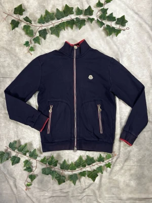 Moncler Maglia Cardigan Zip – Navy – Strl L - "|Färg: Navy, trikolor-detaljer | Modell: Maglia Cardigan Zip, lätt jacka | Storlek: L, normal passform | Skick: Grade A, 9,5/10 | Hör av dig ifall du har funderingar!"