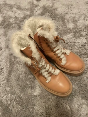  Nya! Steve Madden vinter stövel känga boots med fuskpäls Stl 39 - Säljer ett par camelbruna boots från Steve Madden med vit fuskpäls  och snörning. Skorna har en rejäl plattformsula i gummi och är tillverkade i skinn med foder. Perfekta för kalla dagar och ger en riktigt cozy vinterlook. Endast gått i dem ute i 5 minuter. De är tyvärr för stora för mig . Nypris 2200;-