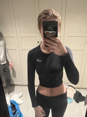 Svart långärmad crop top från NA - Säljer en svart långärmad crop top från NA med tight passform och rund hals. Perfekt för träning eller gymmet. Materialet är stretchigt och följsamt, vilket ger bra rörelsefrihet. Diskret logga på bröstet. Snygg och sportig design. Pris diskuteras gärna 